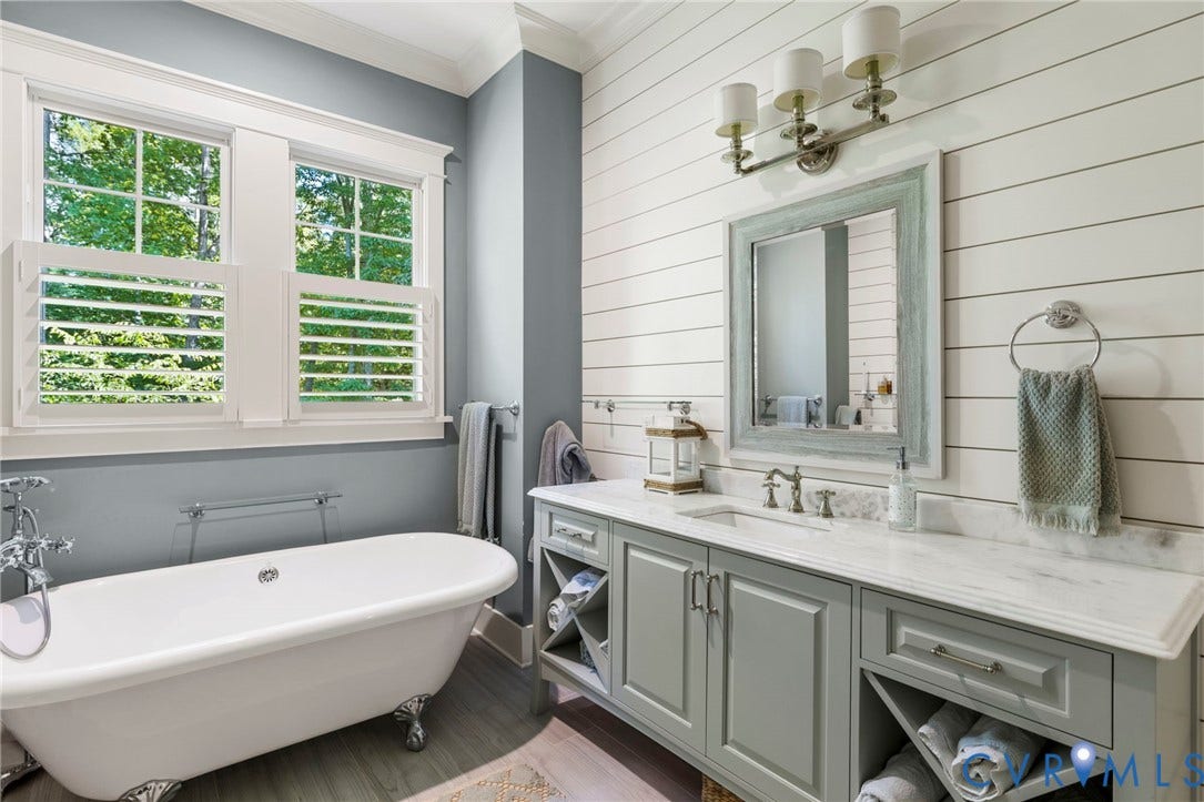 1925 Muswell Court, Hallsley, Midlothian, VA 23112 Freestanding clawfoot tub with chrome fixtures, dual windows with plantation shutters, plank-style accent wall, dual-sink vanity with light-colored countertop, and integrated towel storage