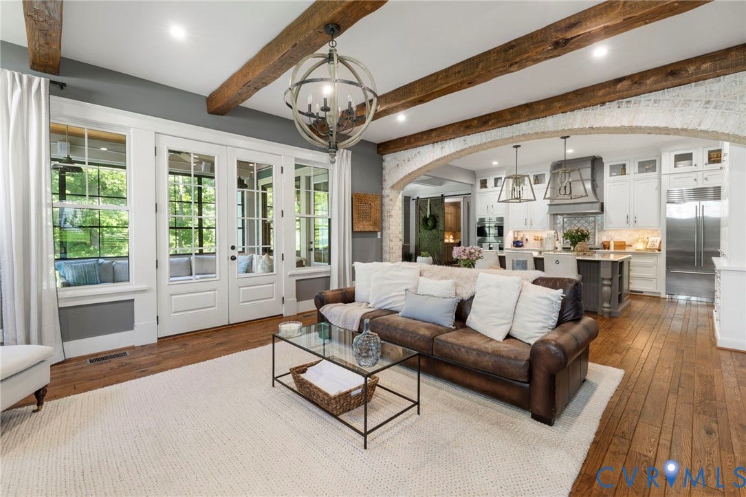 1925 Muswell Court, Hallsley, Midlothian, VA 23112 Open-concept living space featuring wood-finish flooring, exposed ceiling beams, a large arched entryway with brick detailing, and extensive window-paned French doors