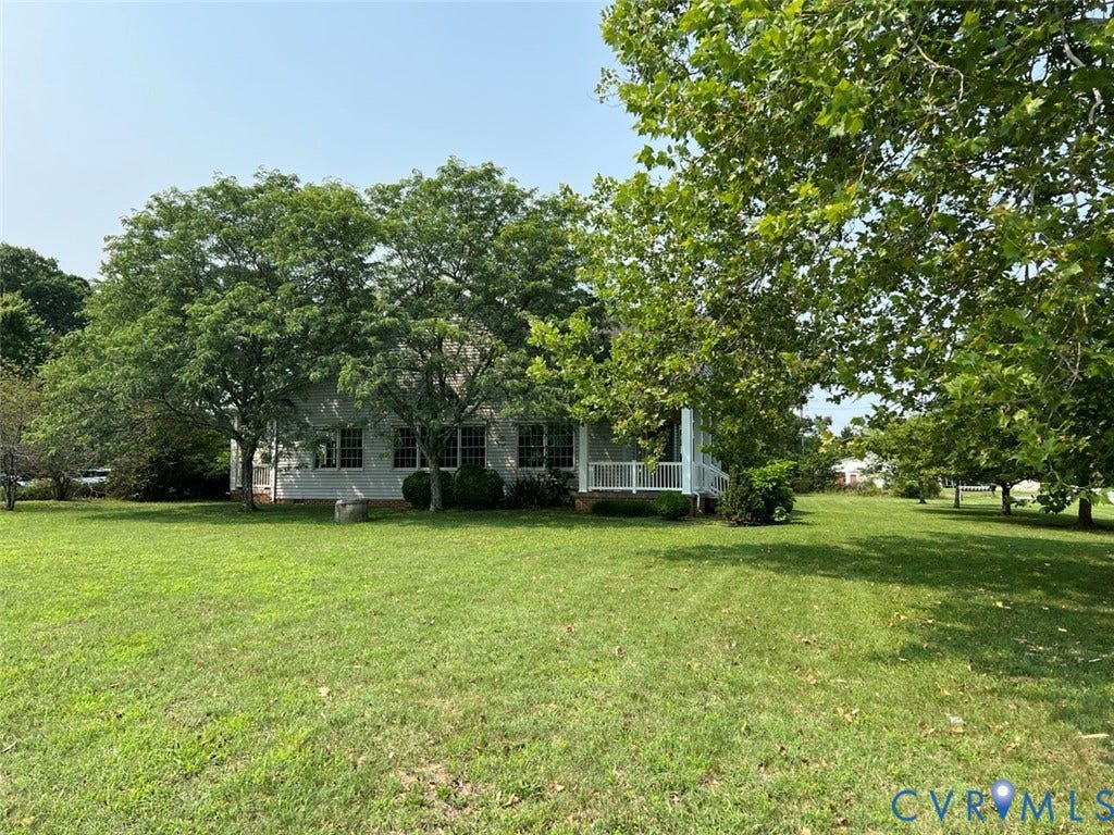 4064 James Madison Highway, Fork Union, VA 23055 Expansive green lawn surrounding a white-sided residence with multiple windows, a covered porch with white railings, and mature trees providing shade