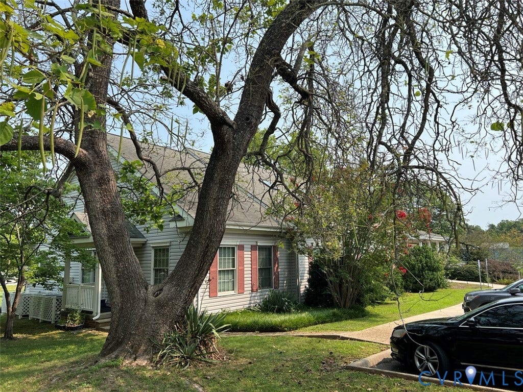 4064 James Madison Highway, Fork Union, VA 23055 Mature trees frame a charming residence featuring horizontal siding, red louvered shutters, and a covered porch with white railing