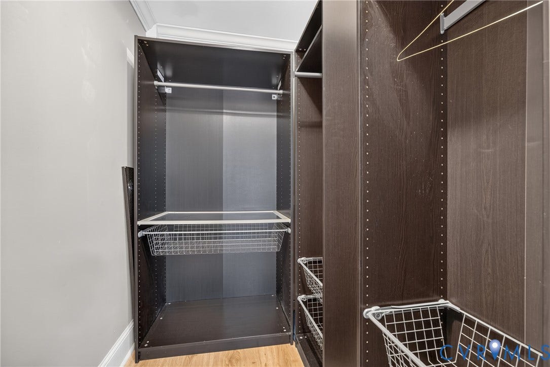 8436 Sir Lionel Place, Kingsland Wood, Ampthill, VA 23237 Custom closet system featuring dark wood-finish cabinetry, adjustable shelving, and integrated wire baskets