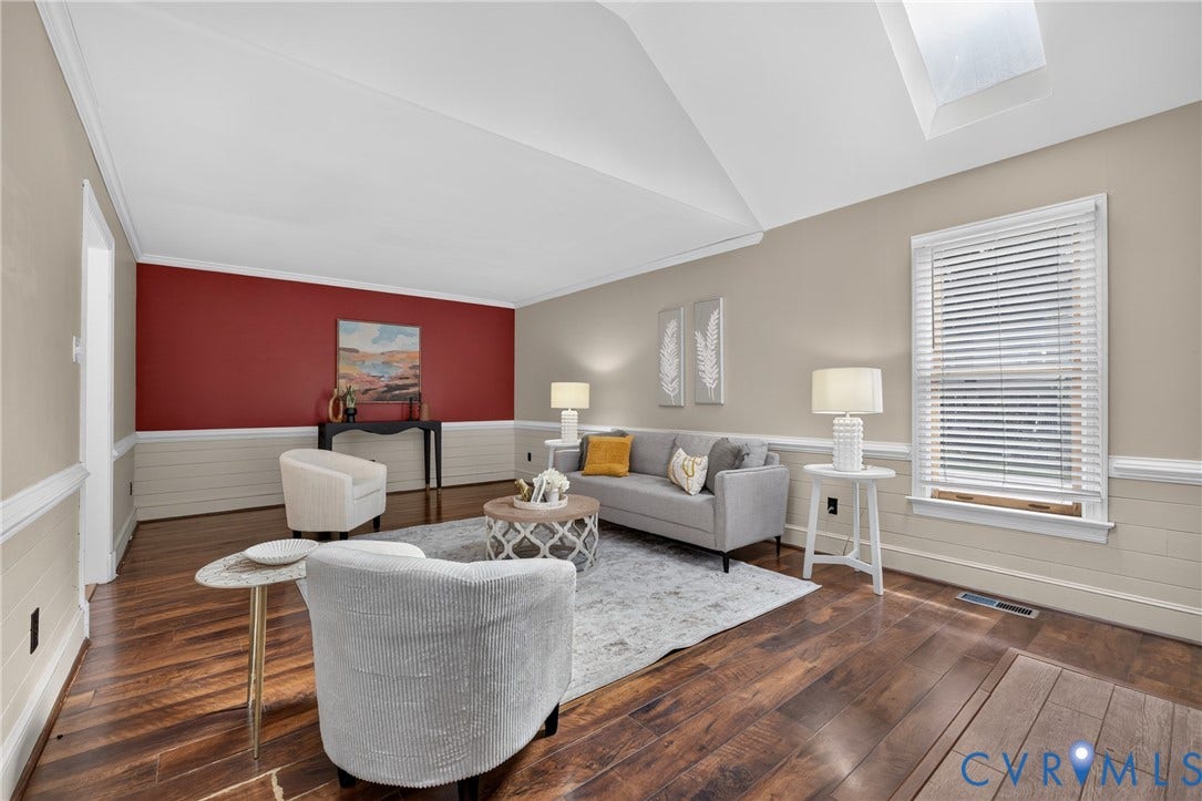 8436 Sir Lionel Place, Kingsland Wood, Ampthill, VA 23237 Sophisticated living room featuring soaring vaulted ceilings with skylights, rich hardwood flooring throughout, and a striking red accent wall with wainscoting detail