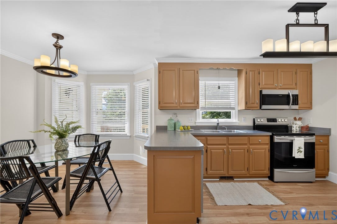 8436 Sir Lionel Place, Kingsland Wood, Ampthill, VA 23237 Open-concept kitchen and dining area featuring warm wood-finish cabinetry, stainless steel appliances, gray quartz countertops, and hardwood flooring throughout