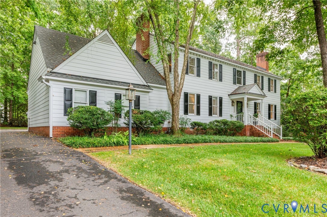 1905 Tunbridge Drive, Henrico, VA 23238 White siding exterior with brick foundation, featuring a covered entry, black window shutters, a paved driveway, and mature landscaping