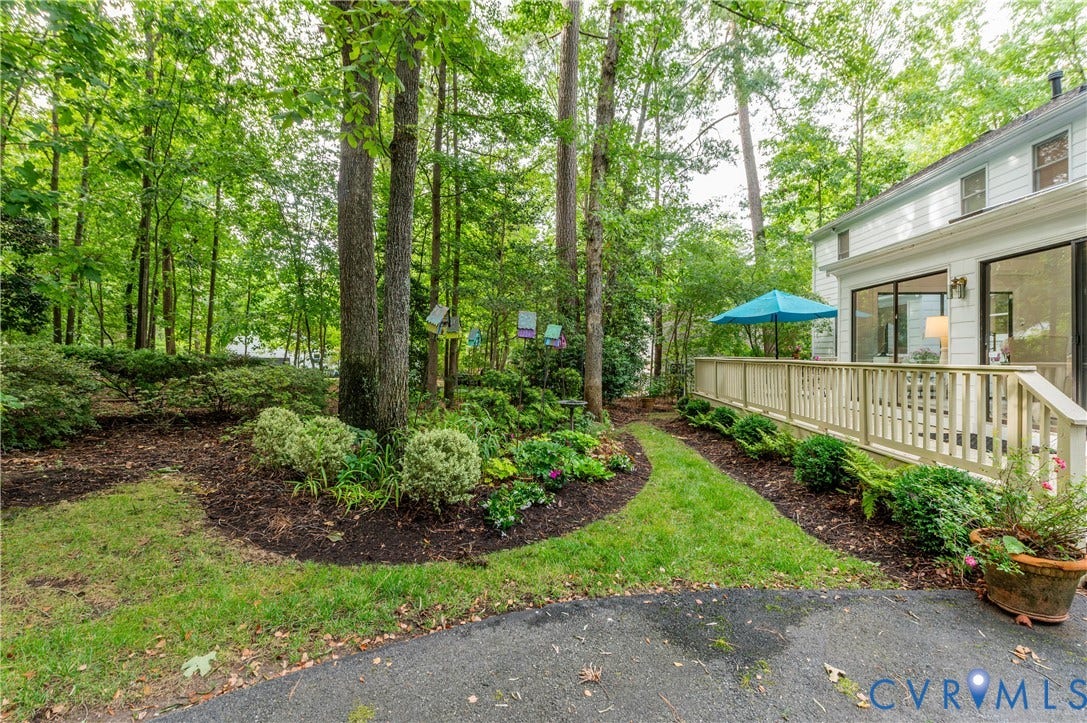 1905 Tunbridge Drive, Henrico, VA 23238 Expansive backyard featuring a wood deck with railings, mature trees, manicured landscaping, a grass pathway, and a white siding exterior with large glass doors