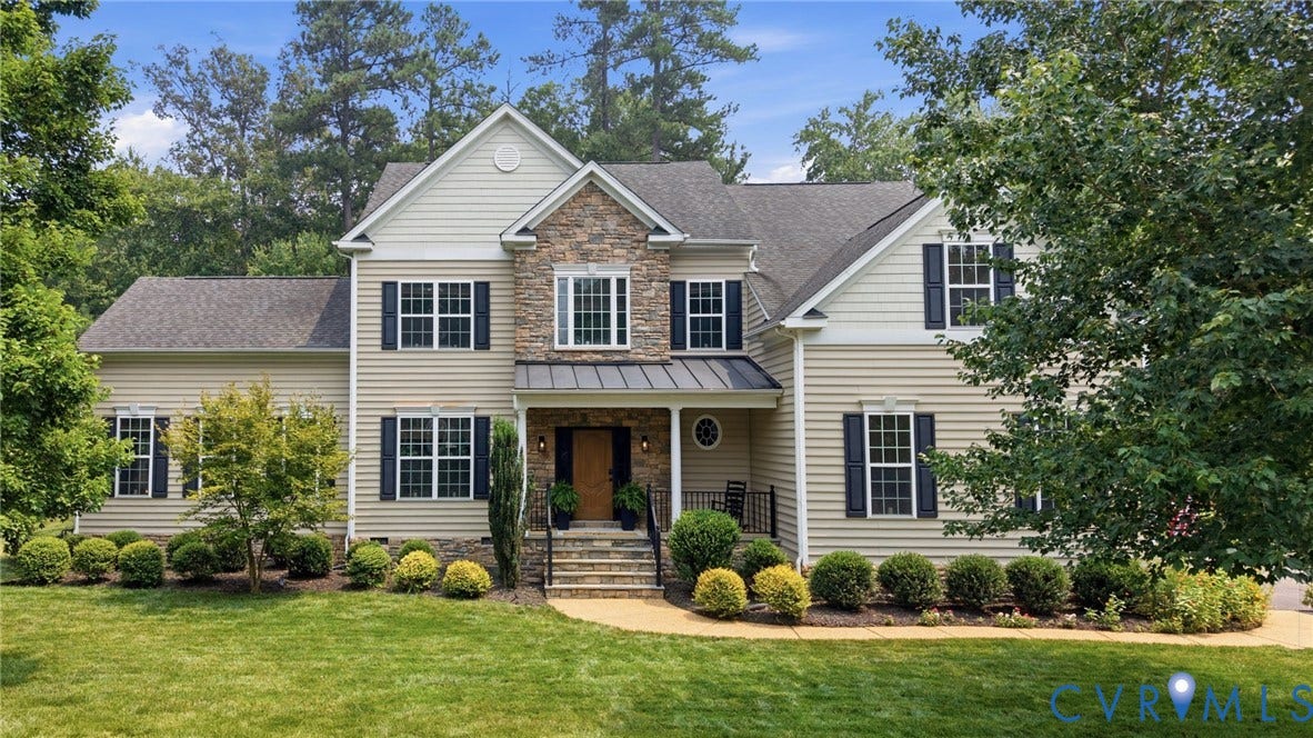 3655 Stone Harbor Drive, Midlothian, VA 23113 Traditional-style residence featuring a stone and siding facade, covered entry with dark metal roof, black window shutters, and a manicured lawn with established landscaping