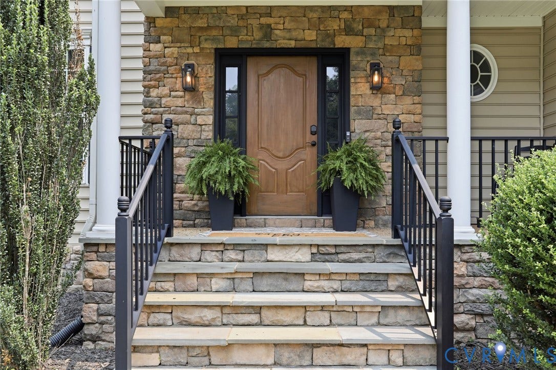 3655 Stone Harbor Drive, Midlothian, VA 23113 Stone facade entry featuring a paneled wooden door, sidelights, and exterior lighting fixtures