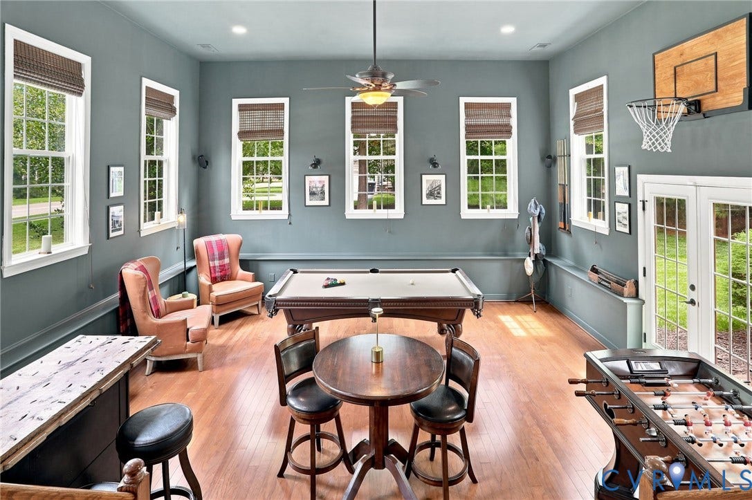 3655 Stone Harbor Drive, Midlothian, VA 23113 Spacious entertainment room featuring wood-finish flooring, high ceilings, multiple windows with blinds, a built-in bar, and double French doors to the exterior