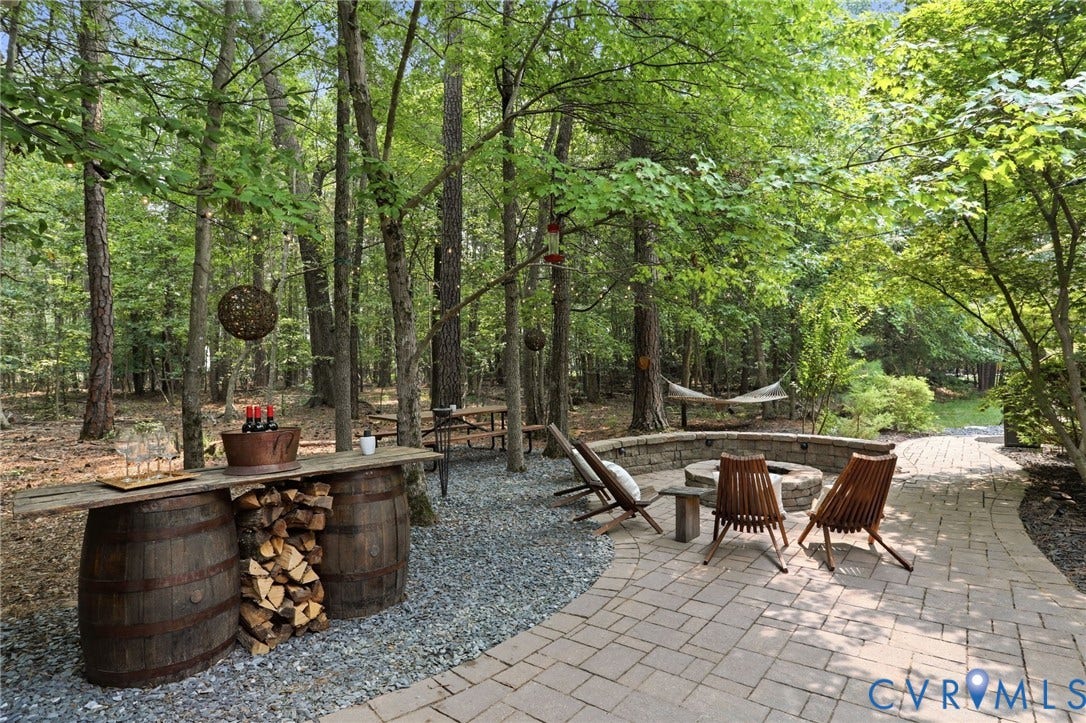 3655 Stone Harbor Drive, Midlothian, VA 23113 Outdoor entertainment area featuring a paver patio, integrated fire pit with stone seating, and a gravel-covered bar area with a wood countertop