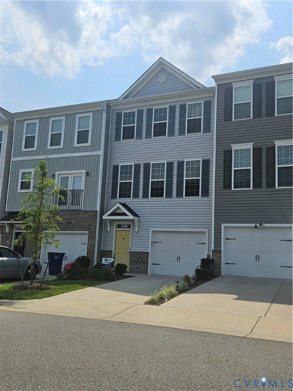11304 Magill Terrace Drive, Chester, VA 23831 Three-story townhome featuring light blue siding, a peaked roofline, and a yellow entry door with an awning