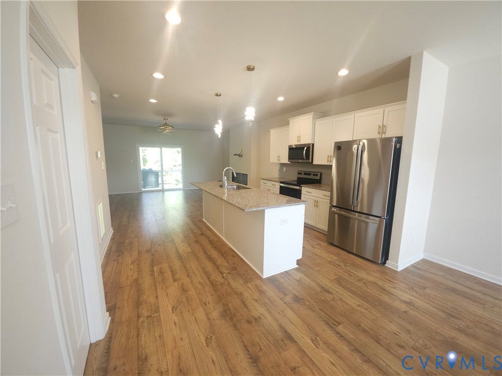 11304 Magill Terrace Drive, Chester, VA 23831 Open-concept kitchen with a central island, stainless steel appliances, white cabinetry, and wood-finish flooring