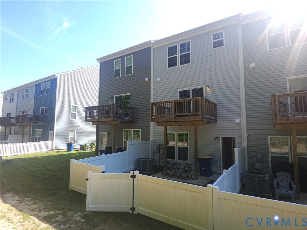 11304 Magill Terrace Drive, Chester, VA 23831 Expansive backyard featuring a manicured lawn, a white picket fence, a lower patio area, an elevated wood deck, and vinyl siding