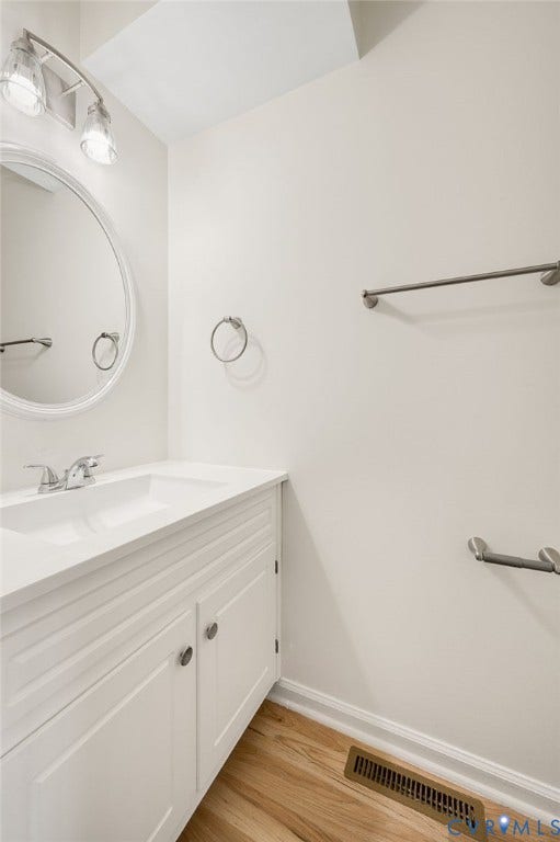 1723 Porter Street, Richmond, VA 23224 Bathroom featuring a white vanity with integrated sink, brushed nickel faucet, and a round wall mirror