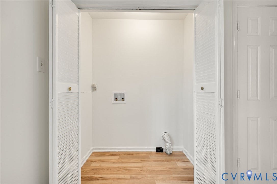 1723 Porter Street, Richmond, VA 23224 Dedicated laundry closet featuring wood-finish flooring, white bifold louvered doors, and utility hookups