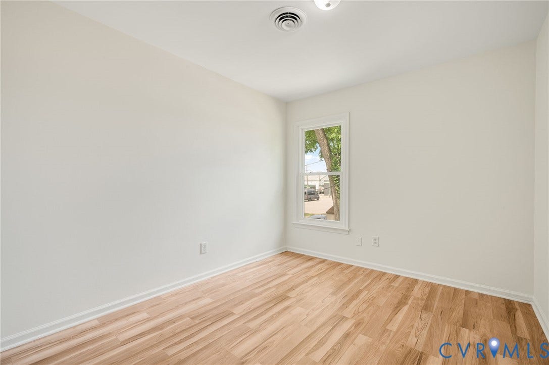 1723 Porter Street, Richmond, VA 23224 Room featuring wood-finish flooring, white baseboards, a single window, white walls, and a ceiling-mounted light fixture