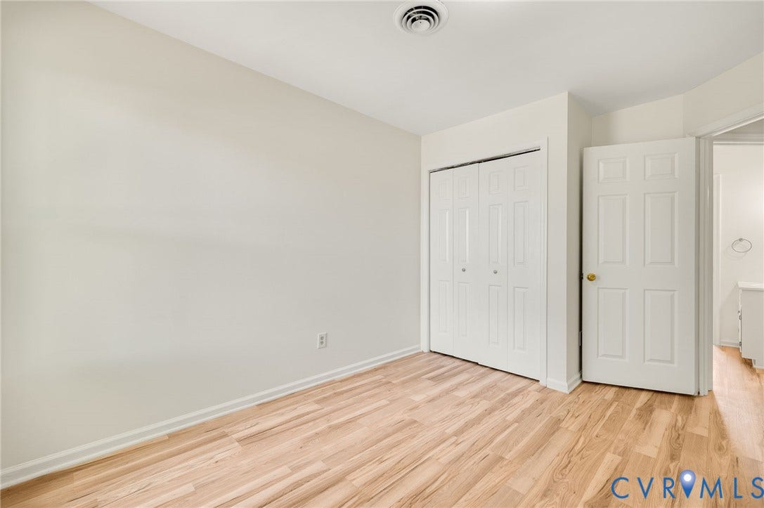 1723 Porter Street, Richmond, VA 23224 Room featuring wood-finish flooring, light-toned walls, bi-fold closet doors, a six-panel interior door, and a ceiling vent