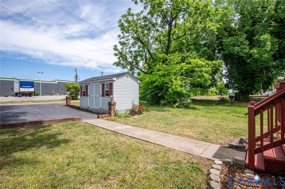 1723 Porter Street, Richmond, VA 23224 Detached storage shed with light-toned siding and red shutters, situated on a grassy lot