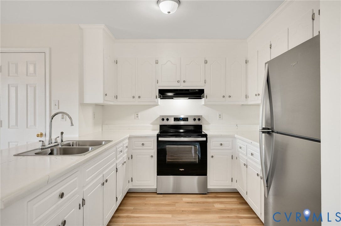 1723 Porter Street, Richmond, VA 23224 Kitchen featuring white cabinetry, stainless steel appliances, wood-finish flooring, and a double-basin sink with a gooseneck faucet