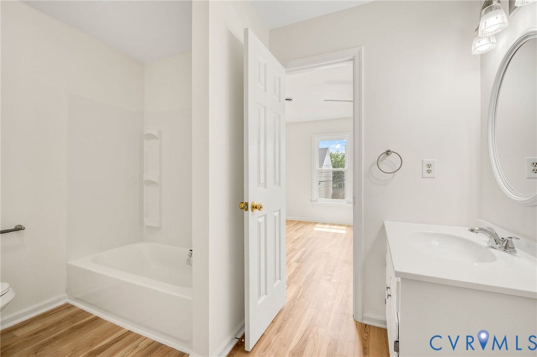 1723 Porter Street, Richmond, VA 23224 Bathroom featuring a white vanity with an integrated sink, an oval mirror, and an adjacent tub/shower combination