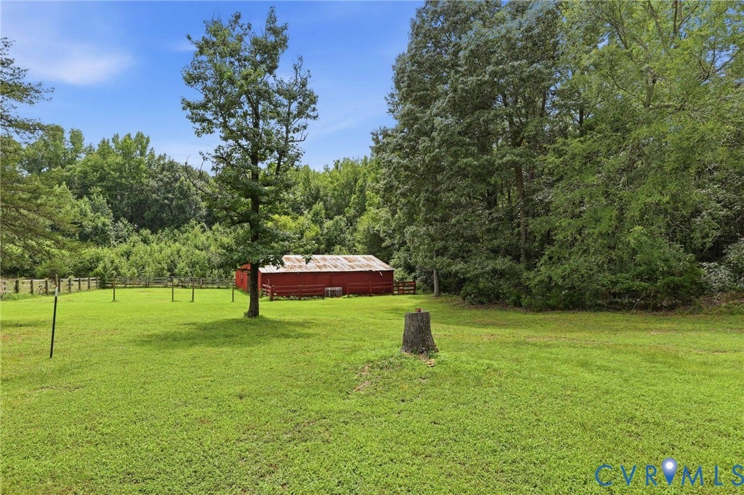 1669 Huguenot Trail, Eastern Powhatan, Powhatan, VA 23139 Expansive green lawn with a red barn structure, bordered by mature trees and a wooden fence