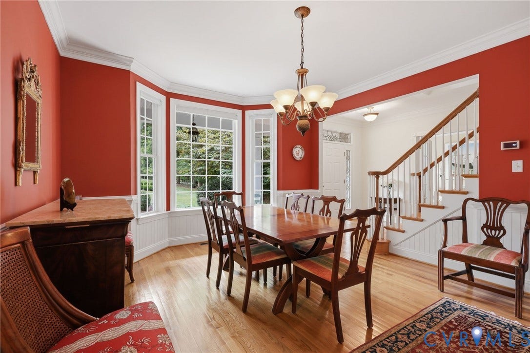 Hardwood flooring throughout, featuring a bay window with multiple panes, crown molding, and wainscoting