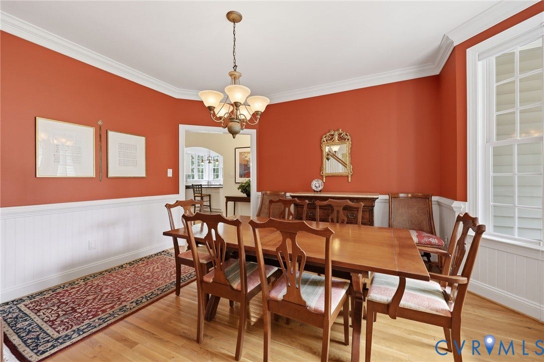 Dining room featuring hardwood flooring, wainscoting, crown molding, and a chandelier