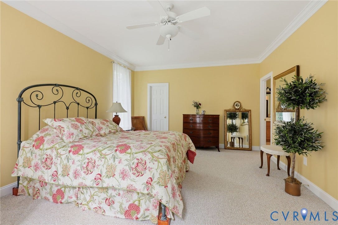 Carpeted room featuring a ceiling fan, crown molding, a white door, and a white window frame with sheer curtains