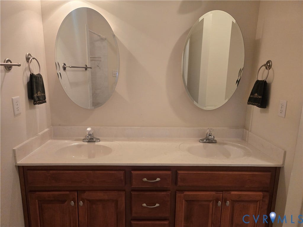 4401 Village Garden Circle, Chester, VA 23831 Dual oval mirrors above a wood-finish double vanity with integrated sinks