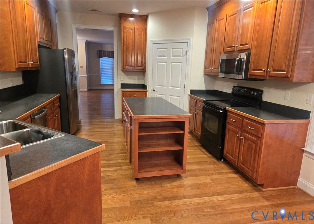 4401 Village Garden Circle, Chester, VA 23831 Kitchen featuring wood engineered flooring, wood cabinetry, dark countertops, and a movable center island