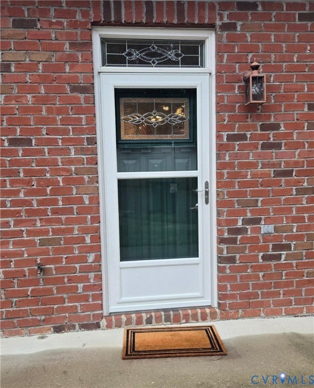 4401 Village Garden Circle, Chester, VA 23831 Brick exterior featuring a white storm door, decorative transom window, and an outdoor wall lantern