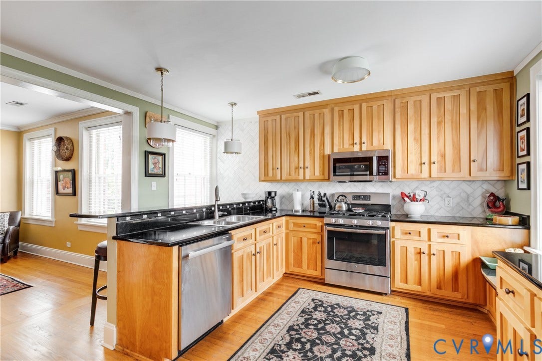 3006 Monument Avenue, #U2W, Museum District, Richmond, VA 23221 Kitchen featuring natural wood cabinetry, stainless steel appliances, black countertops, and a white herringbone tile backsplash