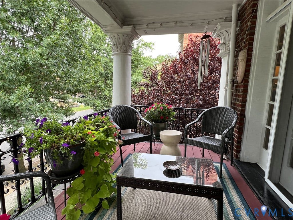 3006 Monument Avenue, #U2W, Museum District, Richmond, VA 23221 Covered porch featuring an ornate Corinthian column, decorative black iron railing, brick exterior, and a painted wood floor