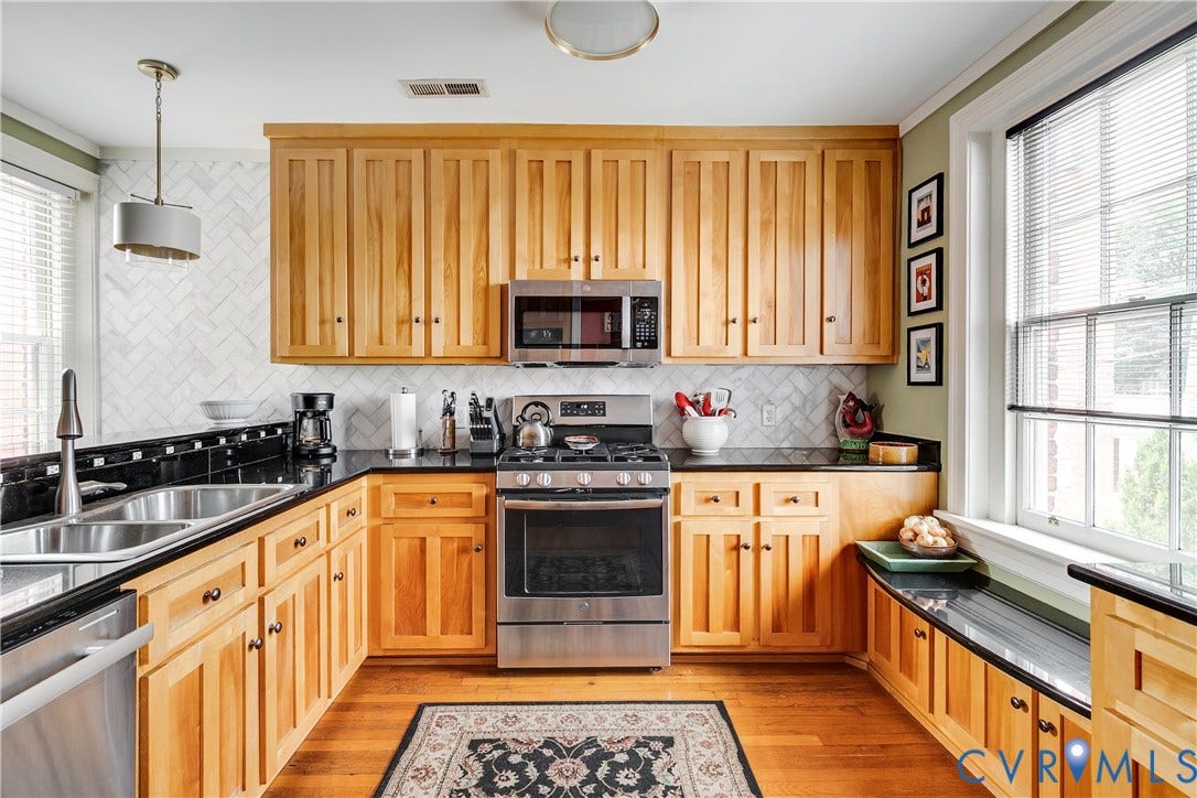 3006 Monument Avenue, #U2W, Museum District, Richmond, VA 23221 U-shaped kitchen featuring wood cabinetry, black countertops, and a herringbone tile backsplash