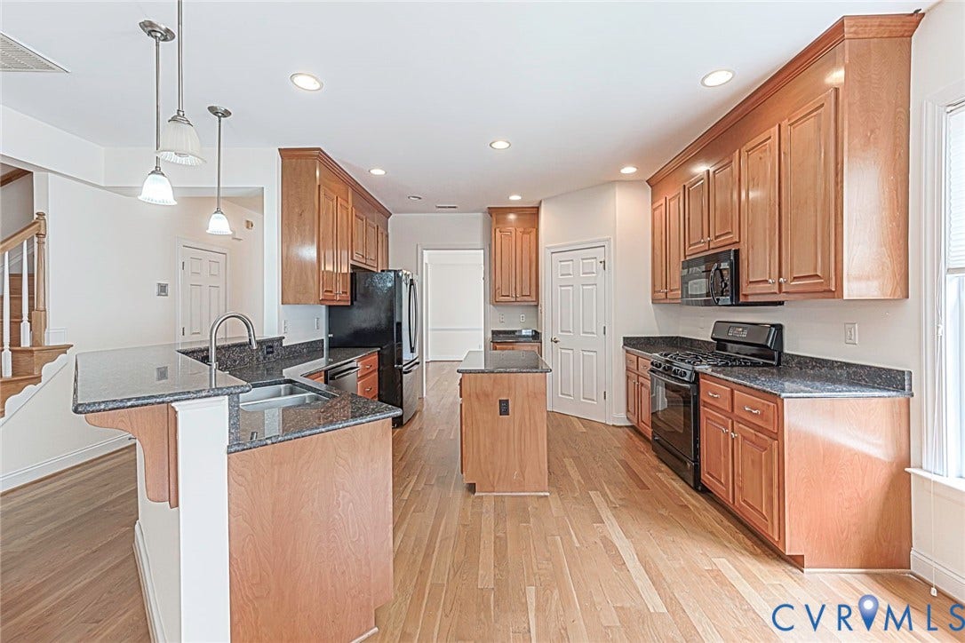 4309 Village Creek Drive, Chester, VA 23831 Kitchen featuring wood-finish flooring, wood cabinetry, dark granite countertops, and a central island and bar, 3 pendant lights over bar.