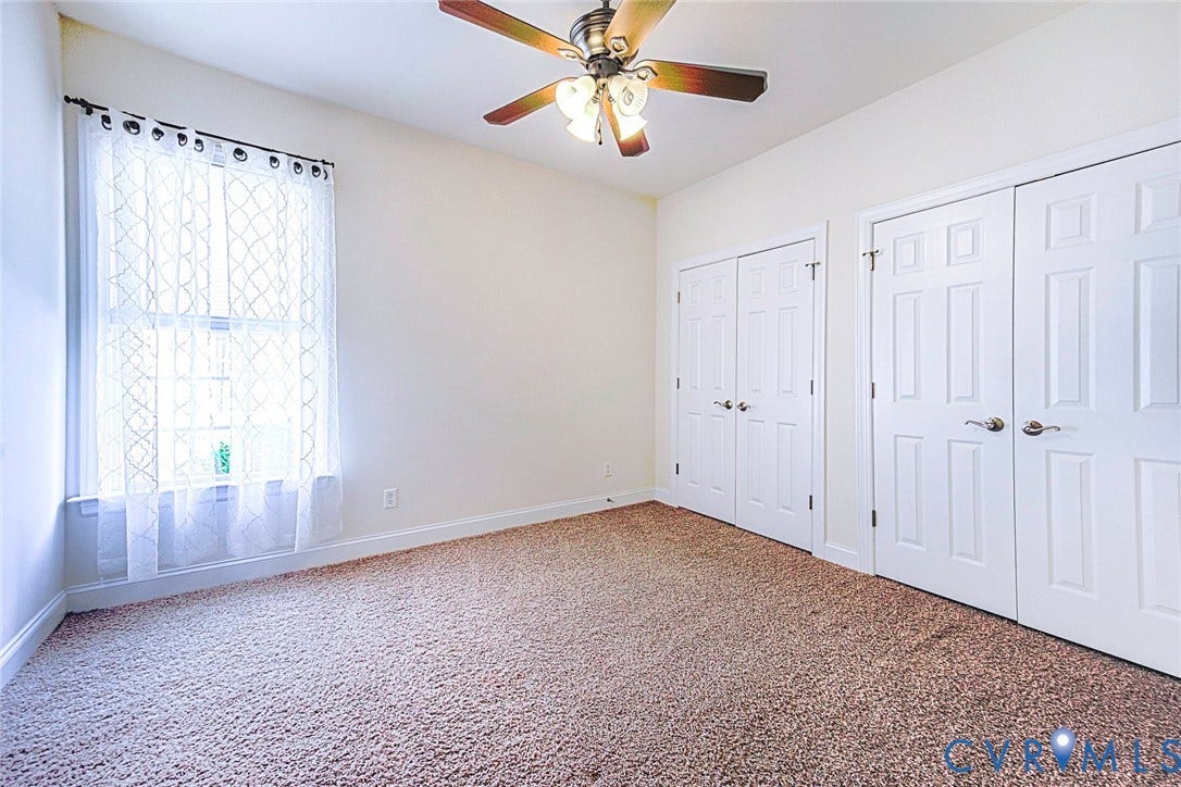 4309 Village Creek Drive, Chester, VA 23831 Carpeted room with a ceiling fan light fixture, a large window, and two sets of bi-fold closet doors