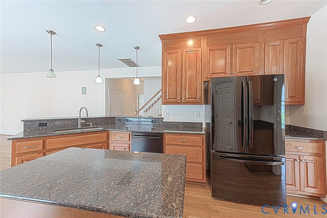 4309 Village Creek Drive, Chester, VA 23831 Kitchen featuring wood cabinetry, dark-toned granite countertops, and an integrated kitchen island with a sink and bar.