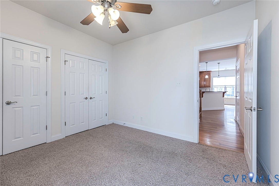 4309 Village Creek Drive, Chester, VA 23831 Carpeted room featuring a ceiling fan, two paneled closet doors, and a paneled entry door