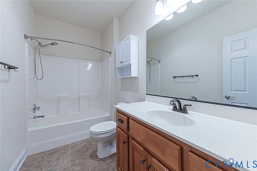 4309 Village Creek Drive, Chester, VA 23831 Bathroom featuring a white tub/shower combination, a single vanity with wood cabinetry, a white countertop, and a large wall-mounted mirror and ceramic tile flooring