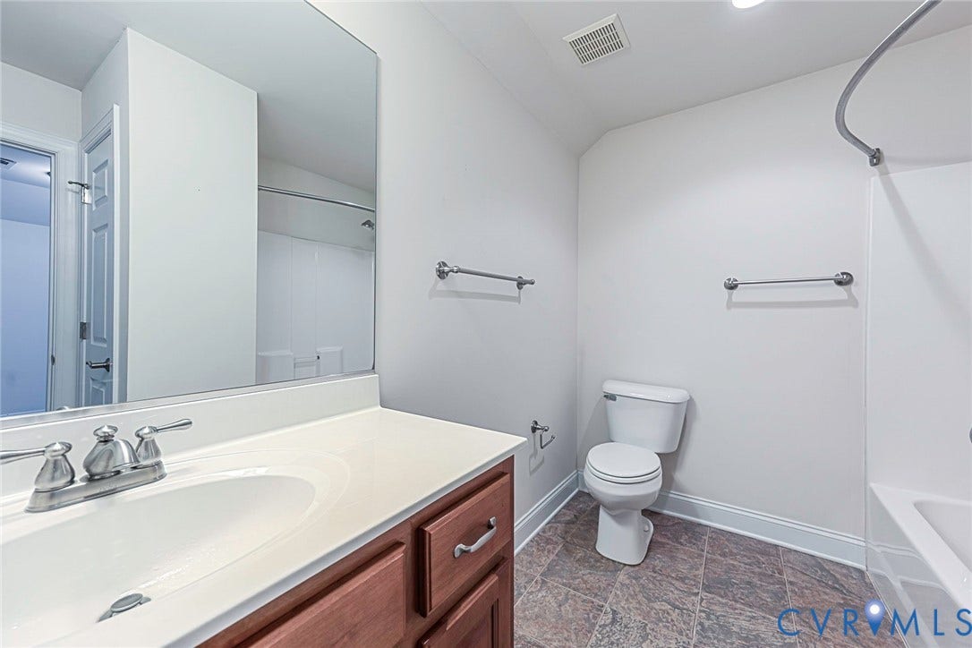 4309 Village Creek Drive, Chester, VA 23831 Bathroom featuring a wood-finish vanity with a white countertop and integrated sink, a large wall-mounted mirror, white toilet, and a combination tub/shower with ceramic tile flooring