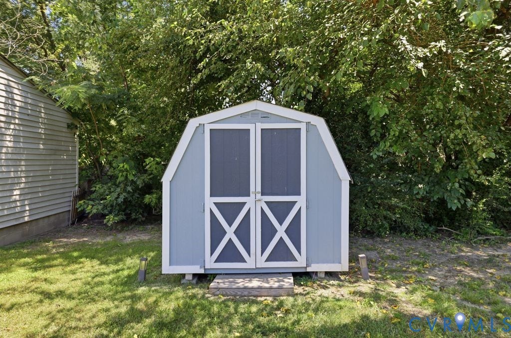 Blue gambrel roof shed with white trim and crossbuck doors