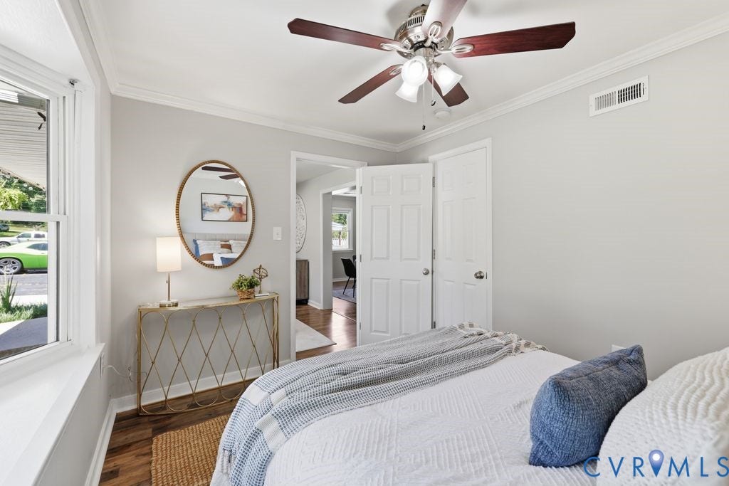 Interior room featuring light-toned walls, crown molding, and wood-finish flooring