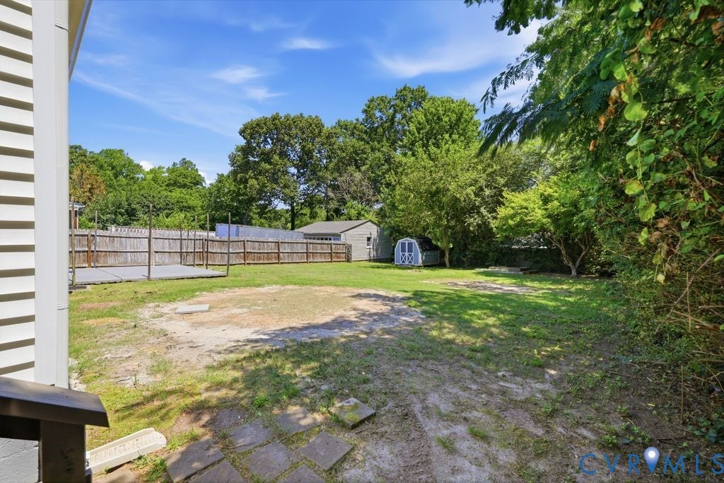Spacious rear yard featuring a wooden fence perimeter, a dedicated deck area, and two storage sheds