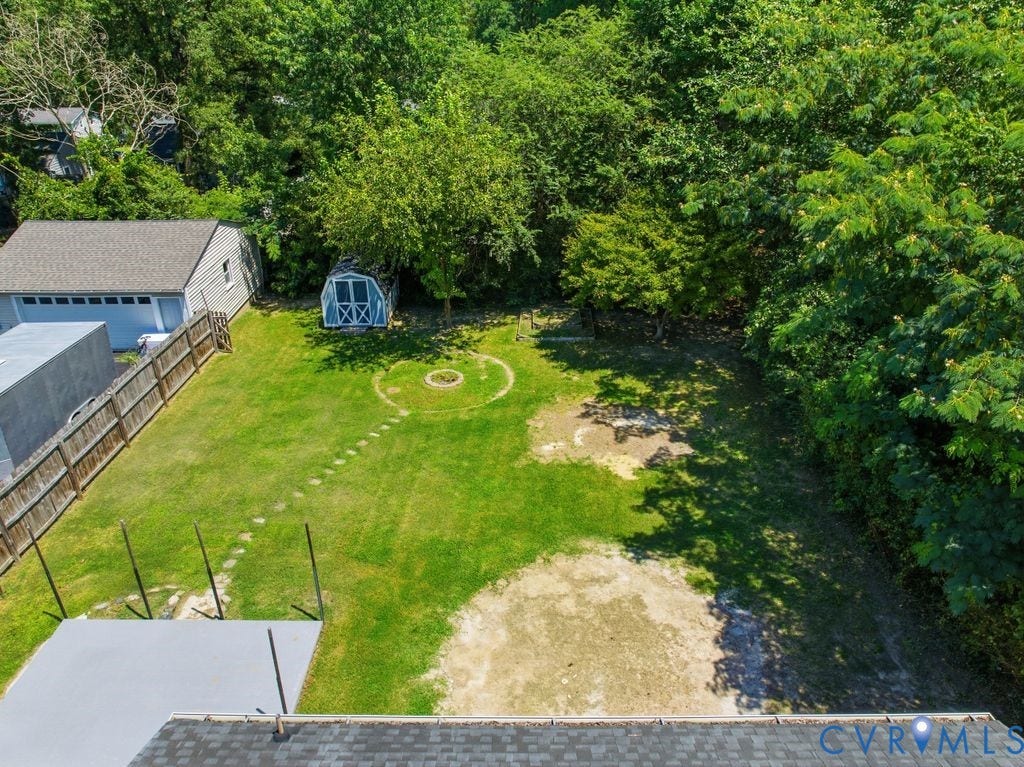 Spacious backyard with a detached garage, wood privacy fencing, and mature perimeter trees