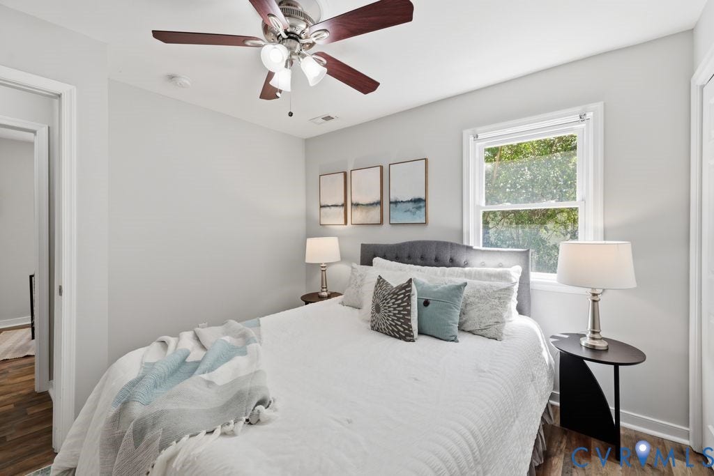 Bedroom featuring wood-finish flooring, a ceiling fan with integrated lighting, and a double-hung window
