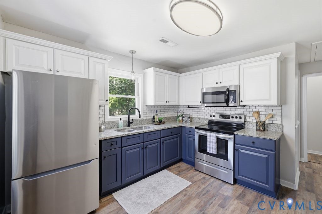 Contemporary kitchen featuring two-tone cabinetry with white upper and blue lower cabinets, stainless steel appliances, granite countertops, and a subway tile backsplash