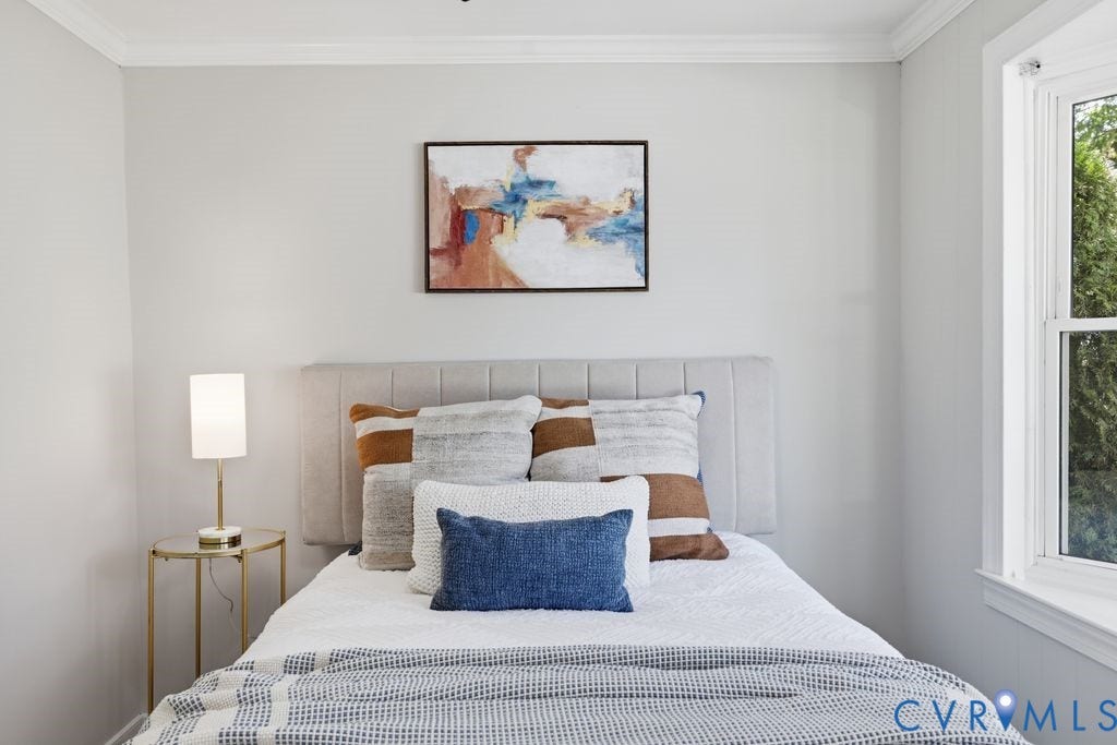 Bright room featuring a tall double-hung window, crown molding, and light gray wall paint
