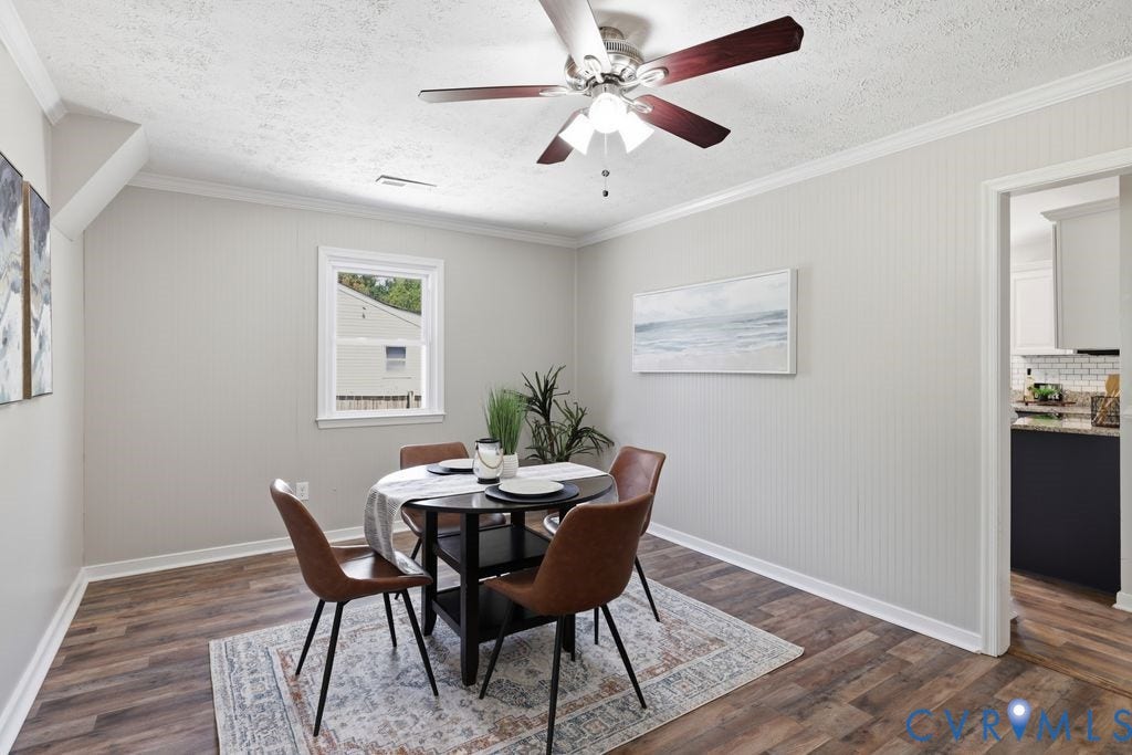 Open dining space featuring wood-finish flooring, a ceiling fan with light fixture, and crown molding