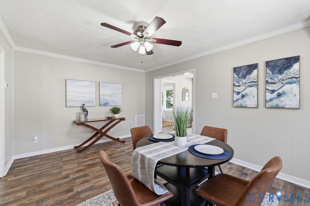 Dining area featuring wood-finish flooring, light-toned walls with wainscoting, and a ceiling fan with integrated lighting