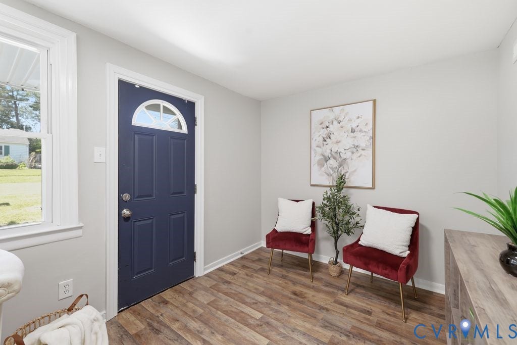 Entryway featuring a navy panel door with an arched transom window, wood-finish flooring, white trim, and light gray walls