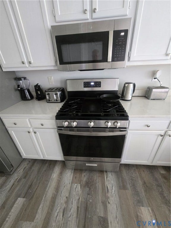 12812 Winfree Street, Chester, VA 23831 Stainless steel gas range with microwave coordinating overhead microwave, white cabinetry, light-toned countertops, and wood-finish flooring